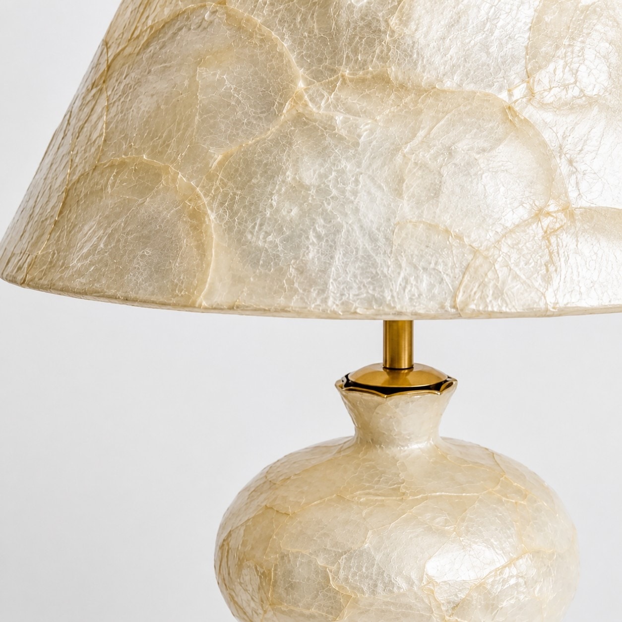 Close view of capiz shell shade, brass-tone stem, and rounded base